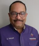 A man with glasses and a mustache wearing purple.